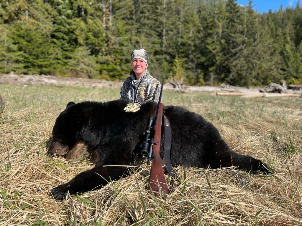 A hunter posing next to a black bear that they killed