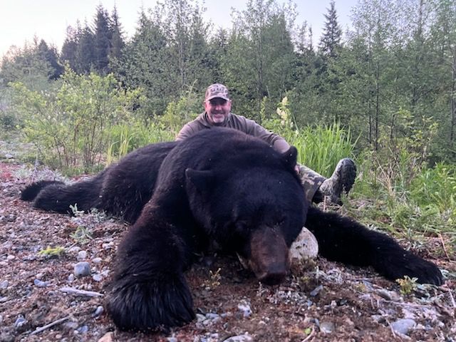 A hunter posing next to a black bear that they killed